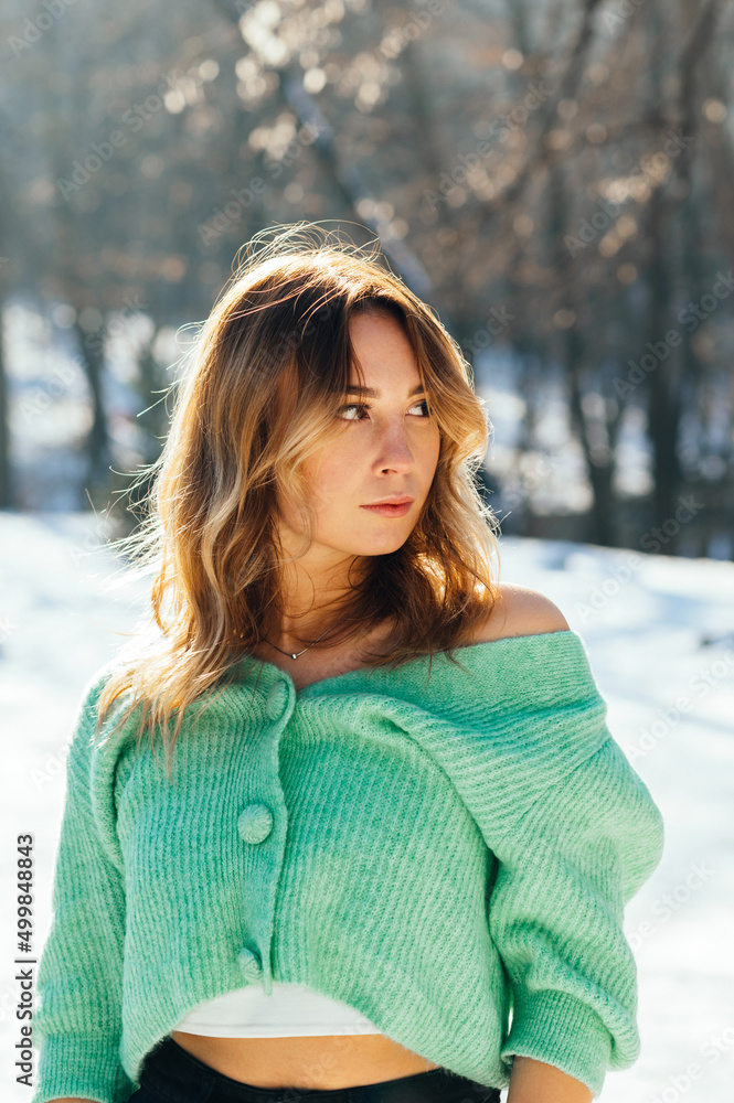 Attractive woman in a sweater posing in the winter in the park, looking away with a serious face. Attractive woman in a sweater posing in the winter in the park, looking away with a serious face.