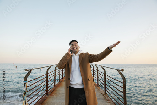 Handsome young Asian man using his smartphone on the beach. Freelance.