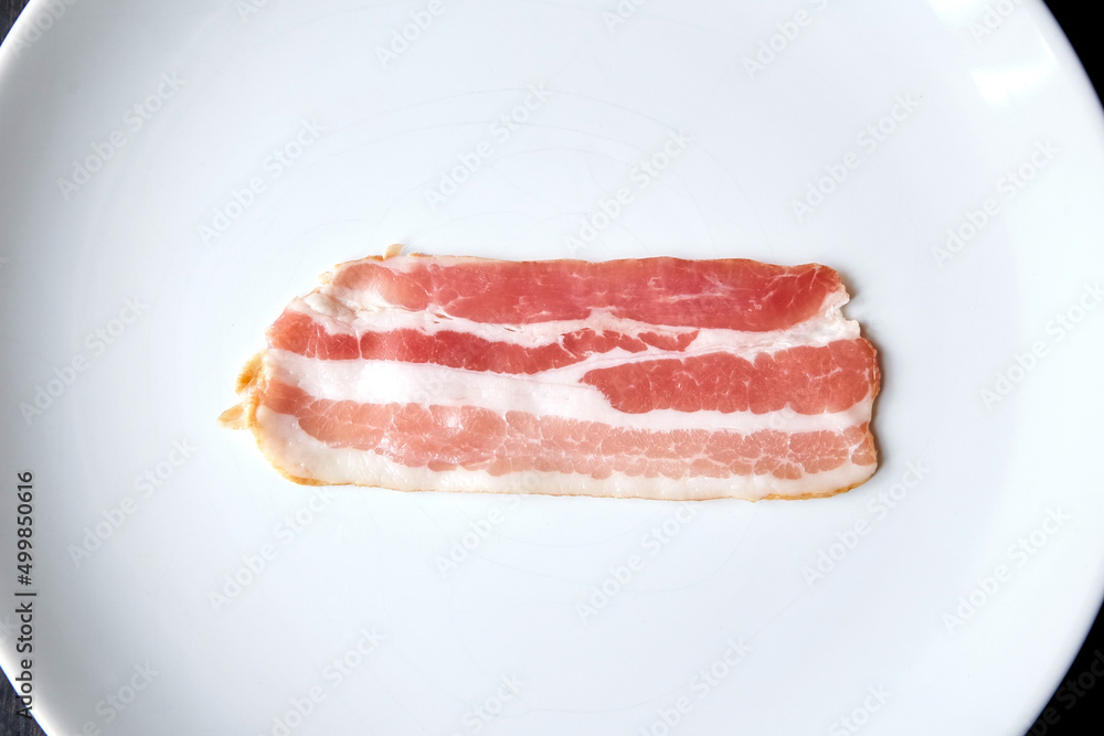 Bacon strip, raw smoked pork meat slice isolated on white Bacon strip, raw smoked pork meat slice isolated on white