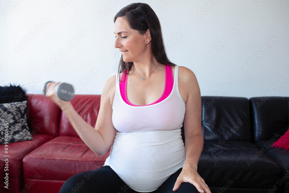 Pregnant woman working out with dumbbell at home Pregnant woman working out with dumbbell at home