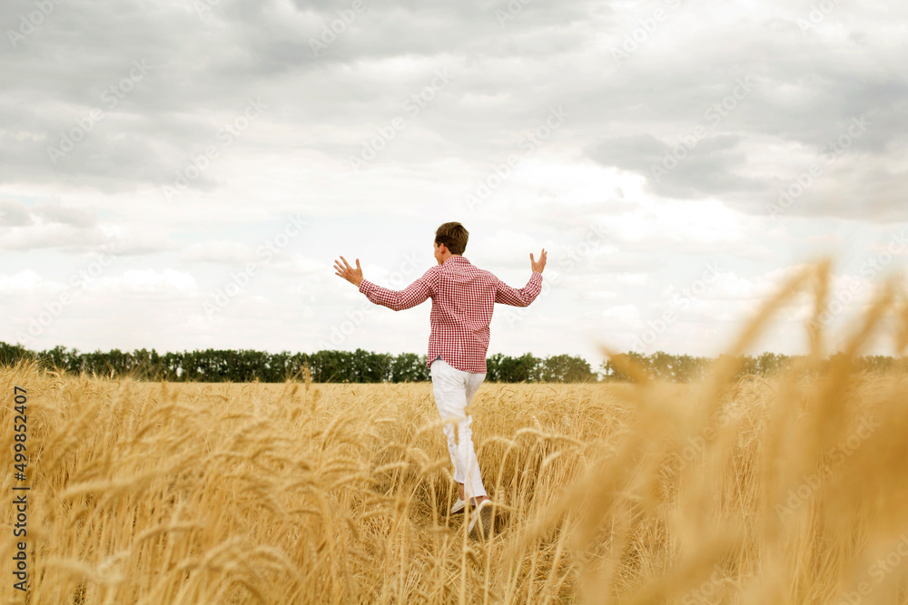 Young happy man with outstretched arms in a wheat field. Concept of freedom Young happy man with outstretched arms in a wheat field. Concept of freedom