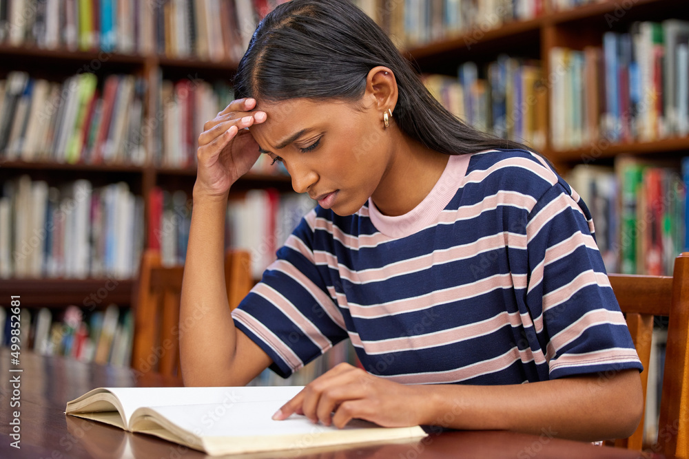 Recipe for success. Shot of a young female student reading a book in a library. Recipe for success. Shot of a young female student reading a book in a library.