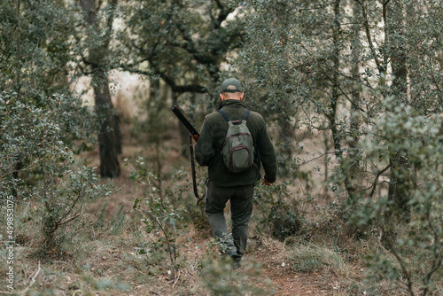 Man with rifle going through trees in forest