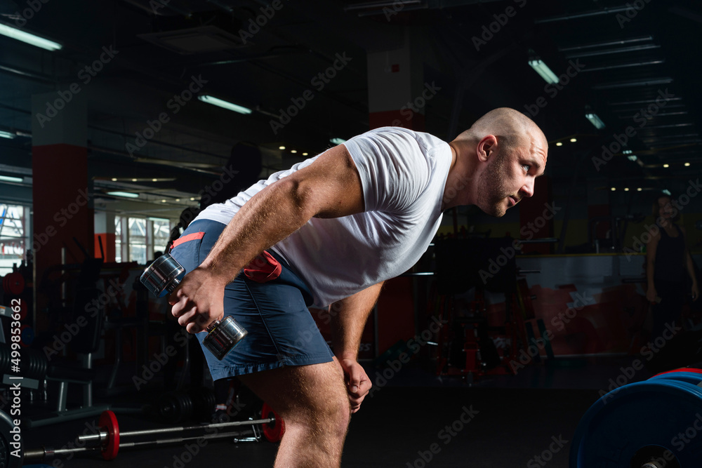 Male bodybuilder engaged with dumbbells in the gym