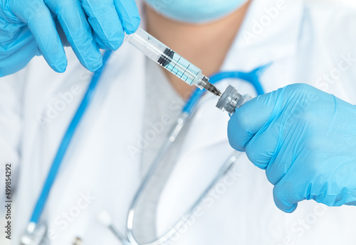 Close up of doctors hands in gloves fills syringe with drug. Ampoule with vaccine for covid-19. Coronavirus