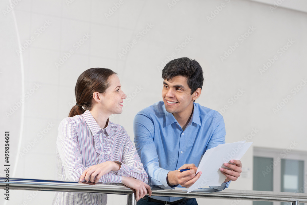 young woman and colleague discuss document young woman and colleague discuss document