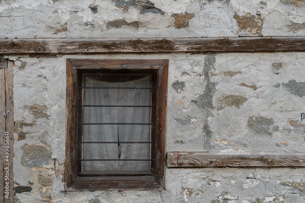 Old wooden window with curtains.Stone wall