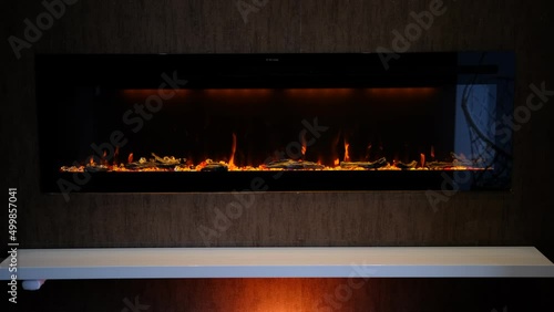 view on electric fireplace with artificial sparkling flame, decor for the interior, orange flame on crystals with orange backlighting.