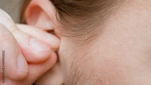 A hand cleans an ear with an ear stick, close-up. Guy with stubble and long hair cleans his ear photo