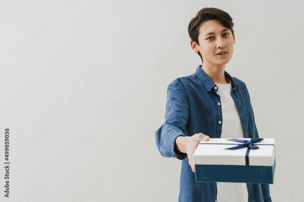 Asian boy with dental braces smiling while posing with gift box Asian boy with dental braces smiling while posing with gift box
