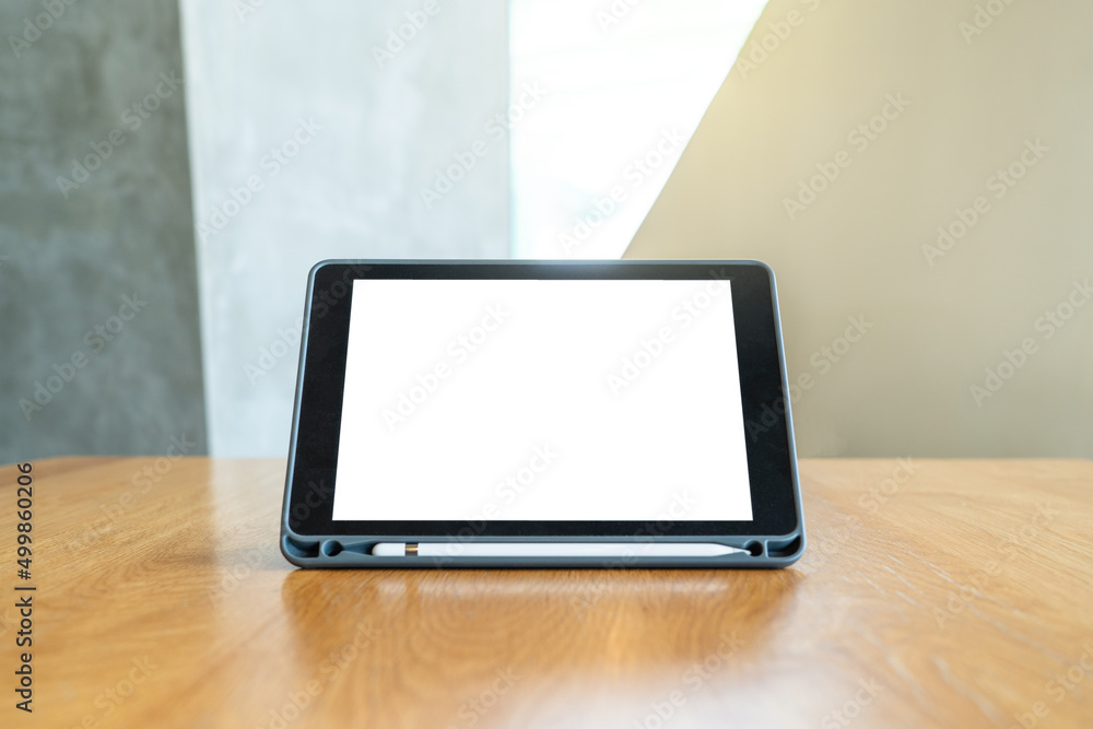 Technology: A black Mock-up tablet stands on a wooden table with working space background and screen clipping path. Technology: A black Mock-up tablet stands on a wooden table with working space background and screen clipping path.