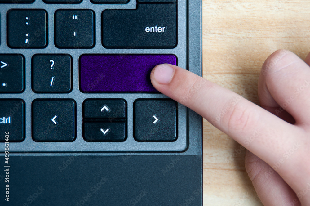 Top view of hand pressing blank purple button on laptop keyboard. Top view of hand pressing blank purple button on laptop keyboard.