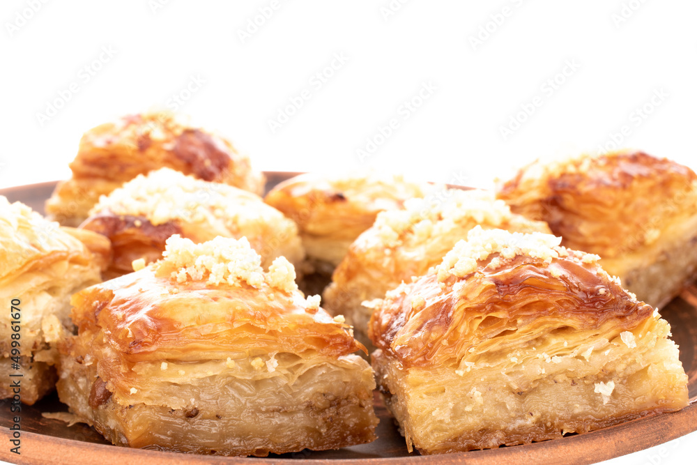 Sweet baklava classic on a clay dish, macro, isolated on a white background. Sweet baklava classic on a clay dish, macro, isolated on a white background.
