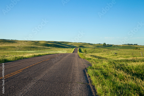 Low angle view of a country road with curves among fields in South Dakota on a summer morning