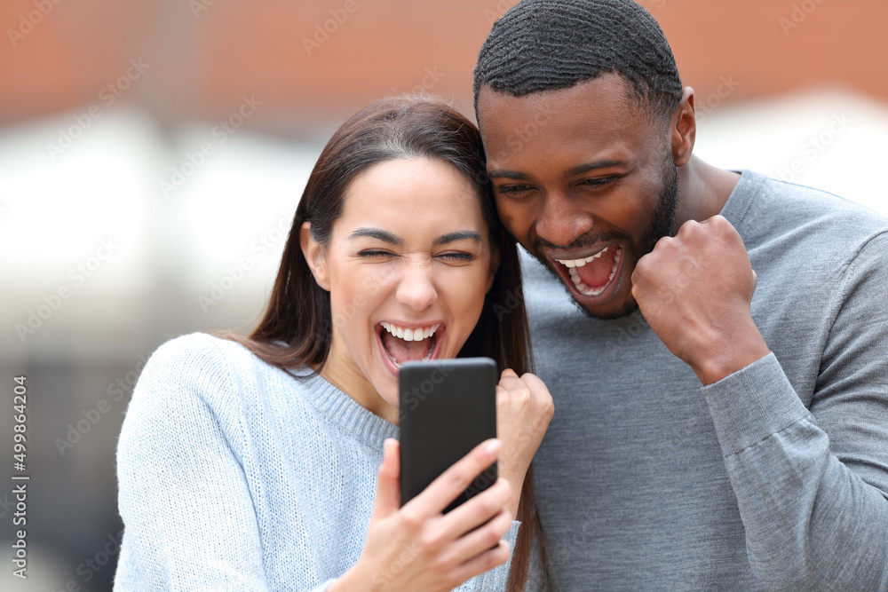 Excited interracial couple checking smart phone Excited interracial couple checking smart phone