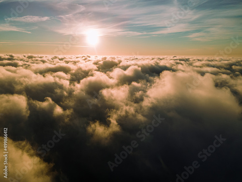 A magical sunset over the clouds. The rays of the sun beautifully pass through the clouds. Above the sky. Fluffy clouds at sunset thickly covered the sky. shooting at high altitude.