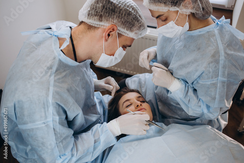 Surgeon and his assistant performing cosmetic surgery on nose in hospital operating room. Nose reshaping, augmentation. Rhinoplasty.