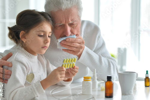 Granddaughter giving medicine to her grandfather in room