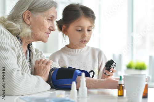 Cute girl and senior woman measuring blood pressure