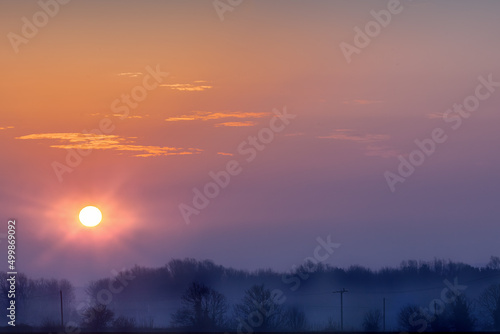 Fototapeta Naklejka Na Ścianę i Meble -  Sunrise over rural misty trees in Norfolk with orange dawn sky