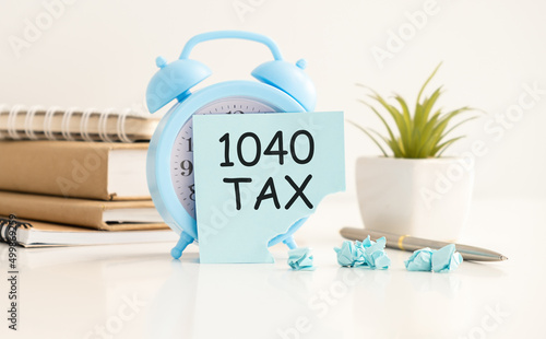 On the desktop are reports, notebooks, an alarm clock and a blue sticker with the text 1040 tax