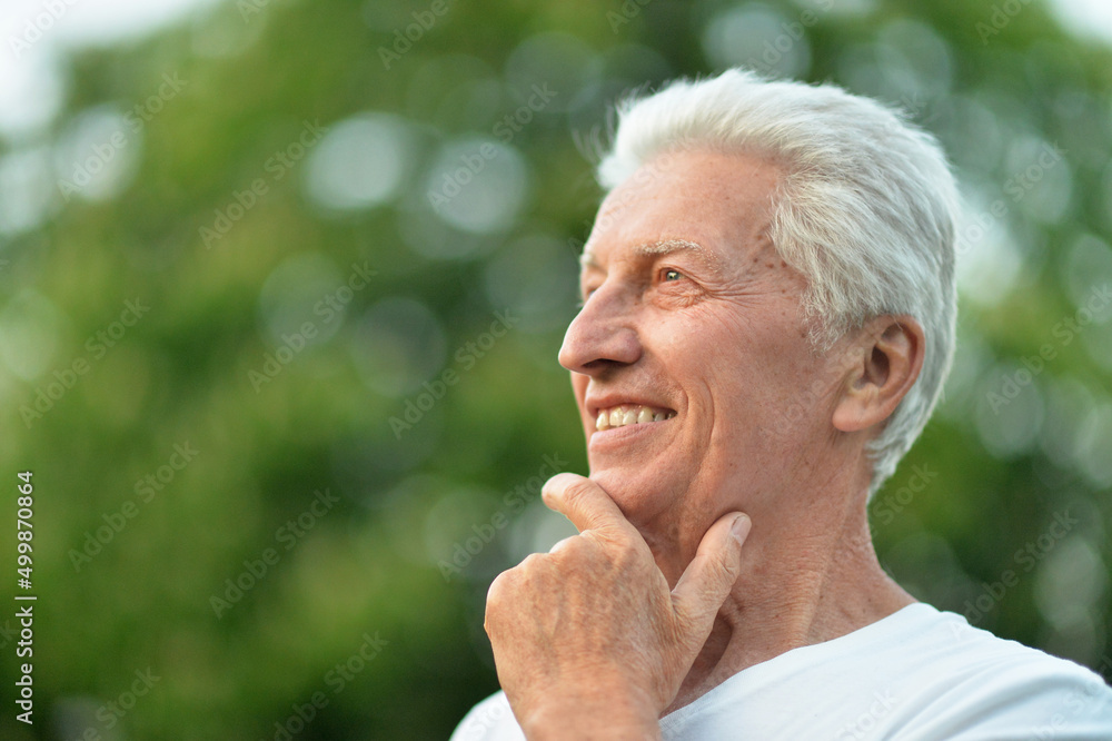 Beautiful smiling senior man posing in summer park Beautiful smiling senior man posing in summer park