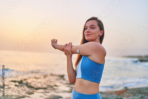 Satisfied one fitness slim diabetic patient woman doing hands stretching exercises by the sea. Healthy habits and active sugar diabetes lifestyle photo