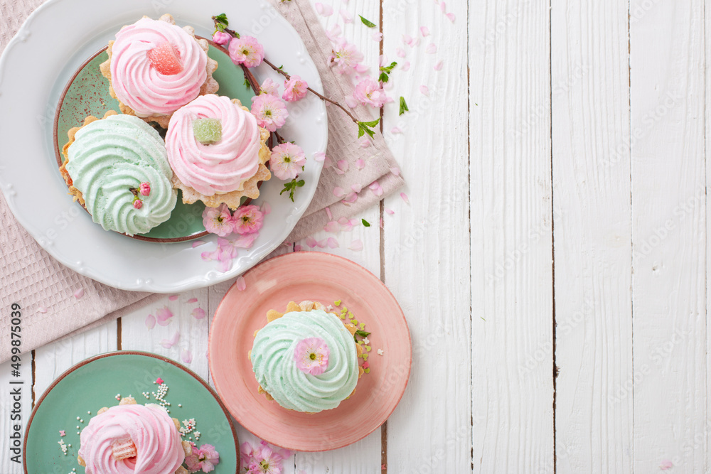 pink and green cupcakes with spring flowers on white wooden background
