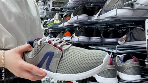 Someone chooses large-sized gray unisex sneakers at the sporting goods store