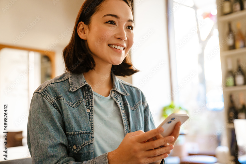 Young asian woman smiling and using mobile phone Young asian woman smiling and using mobile phone