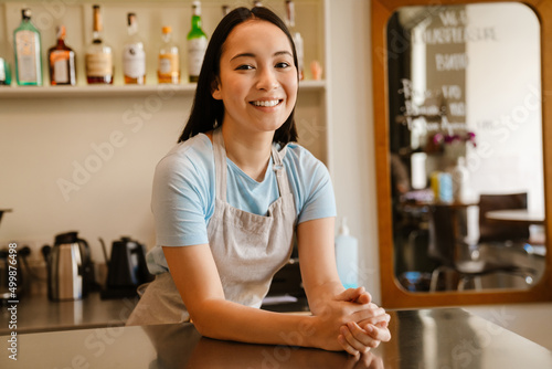 Young asian barista wearing apron smiling in cafe