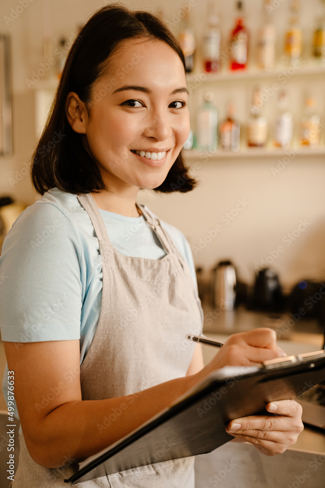 Young asian barista wearing apron smiling in cafe Young asian barista wearing apron smiling in cafe