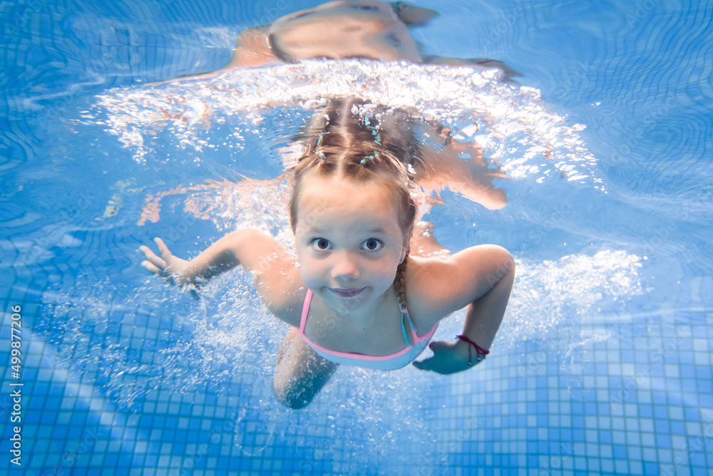 Little girl swims under water in paddling pool. Diving. Learning child ...
