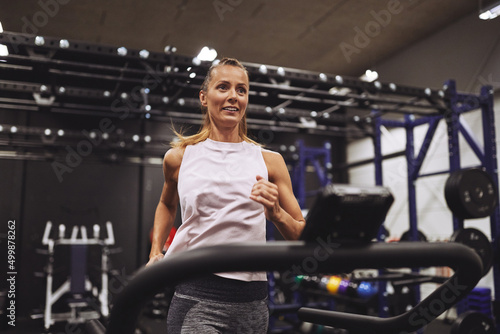Fit mature woman smiling while running on a treadmill