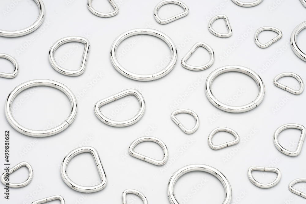 Metal accessories and supplies for making of bags and backpacks. Chrome-plated metal frames laying on a grey background. Sewing accessories, bags making Metal accessories and supplies for making of bags and backpacks. Chrome-plated metal frames laying on a grey background. Sewing accessories, bags making