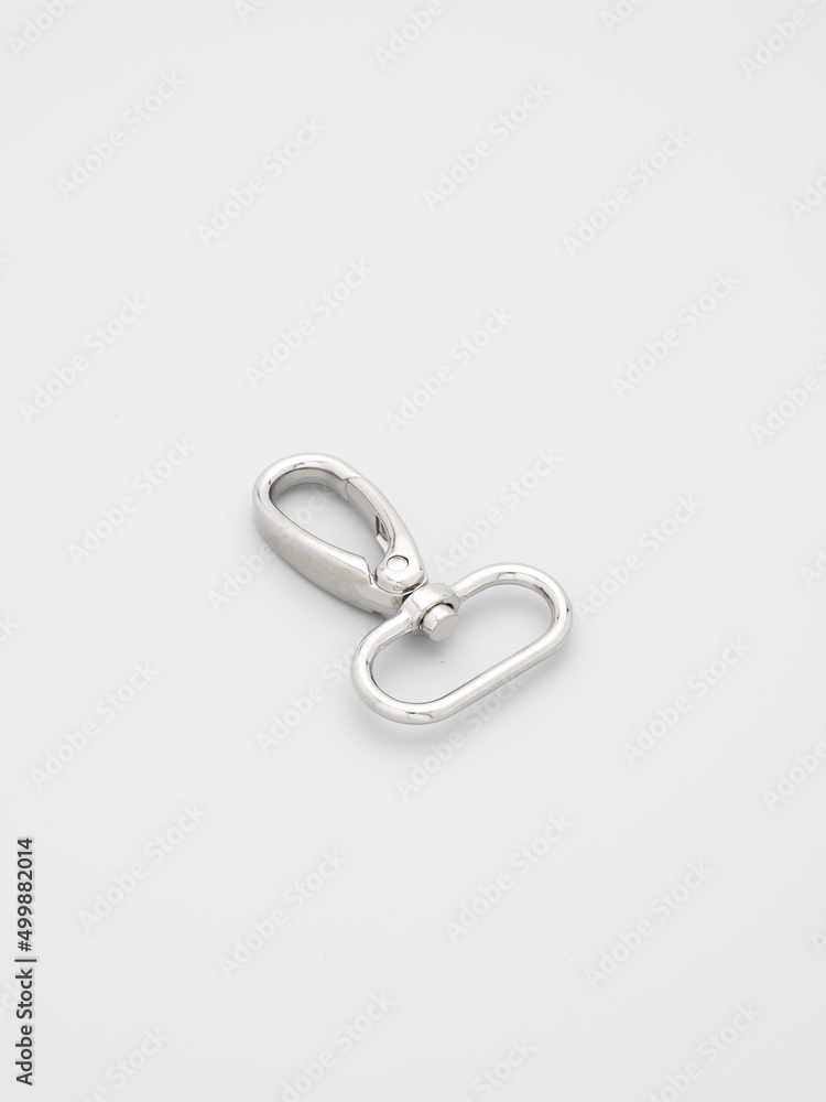 The heap of metal lobster claw clasp for making bags and backpacks lying on a gray background. Chrome-plated metal accessories and supplies for bags, backpacks. Handbags making, copy space The heap of metal lobster claw clasp for making bags and backpacks lying on a gray background. Chrome-plated metal accessories and supplies for bags, backpacks. Handbags making, copy space