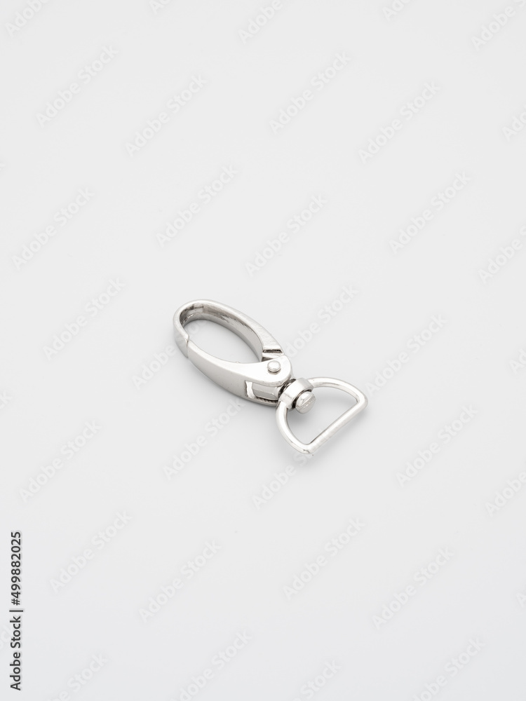 The heap of metal lobster claw clasp for making bags and backpacks lying on a gray background. Chrome-plated metal accessories and supplies for bags, backpacks. Handbags making, copy space The heap of metal lobster claw clasp for making bags and backpacks lying on a gray background. Chrome-plated metal accessories and supplies for bags, backpacks. Handbags making, copy space