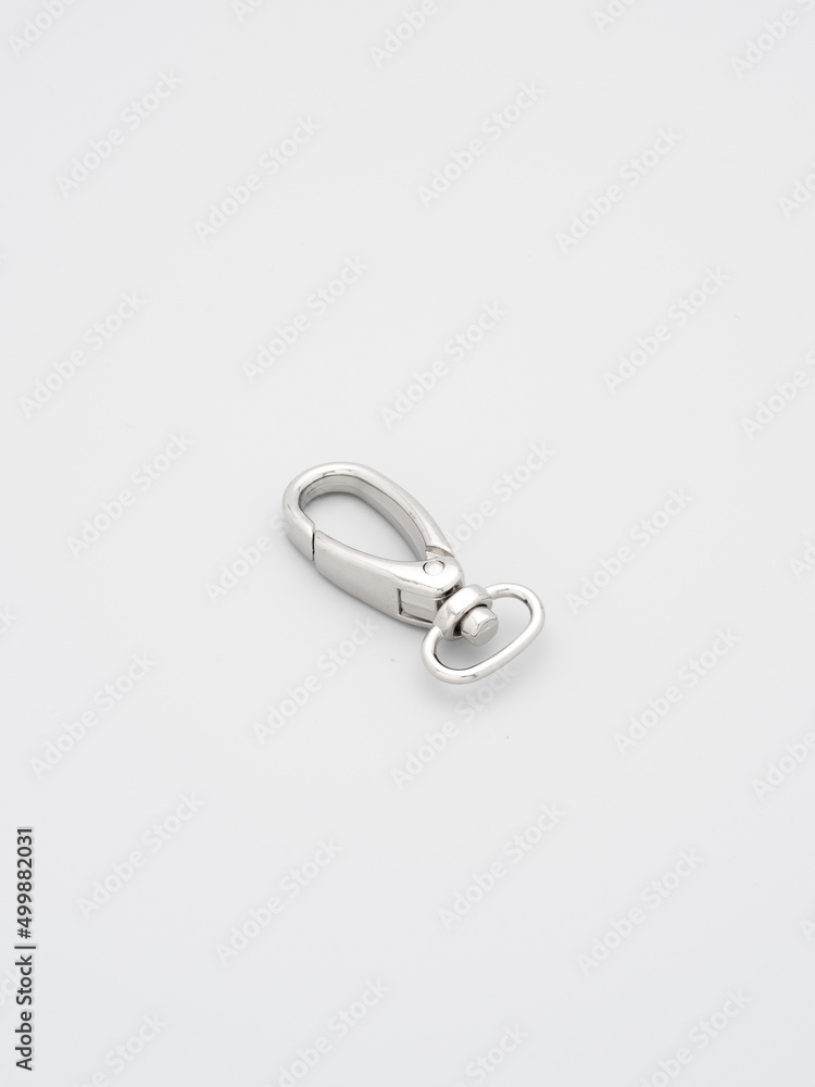 The heap of metal lobster claw clasp for making bags and backpacks lying on a gray background. Chrome-plated metal accessories and supplies for bags, backpacks. Handbags making, copy space The heap of metal lobster claw clasp for making bags and backpacks lying on a gray background. Chrome-plated metal accessories and supplies for bags, backpacks. Handbags making, copy space