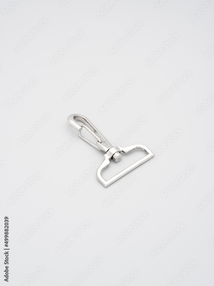 The heap of metal lobster claw clasp for making bags and backpacks lying on a gray background. Chrome-plated metal accessories and supplies for bags, backpacks. Handbags making, copy space The heap of metal lobster claw clasp for making bags and backpacks lying on a gray background. Chrome-plated metal accessories and supplies for bags, backpacks. Handbags making, copy space