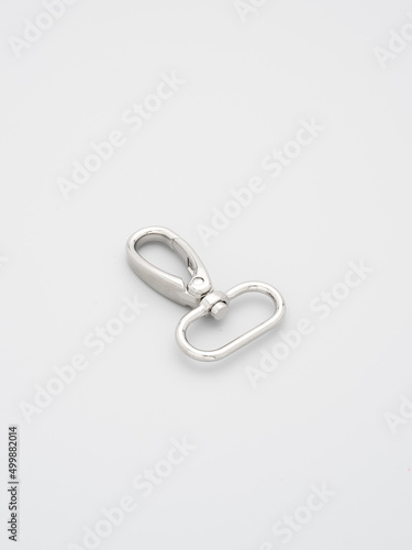 The heap of metal lobster claw clasp for making bags and backpacks lying on a gray background. Chrome-plated metal accessories and supplies for bags, backpacks. Handbags making, copy space