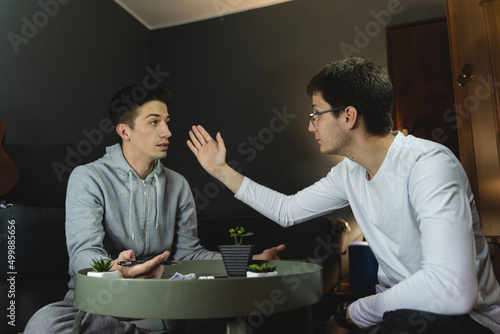 Two friends are playing a board game with dices while arguing and laughing together in a room