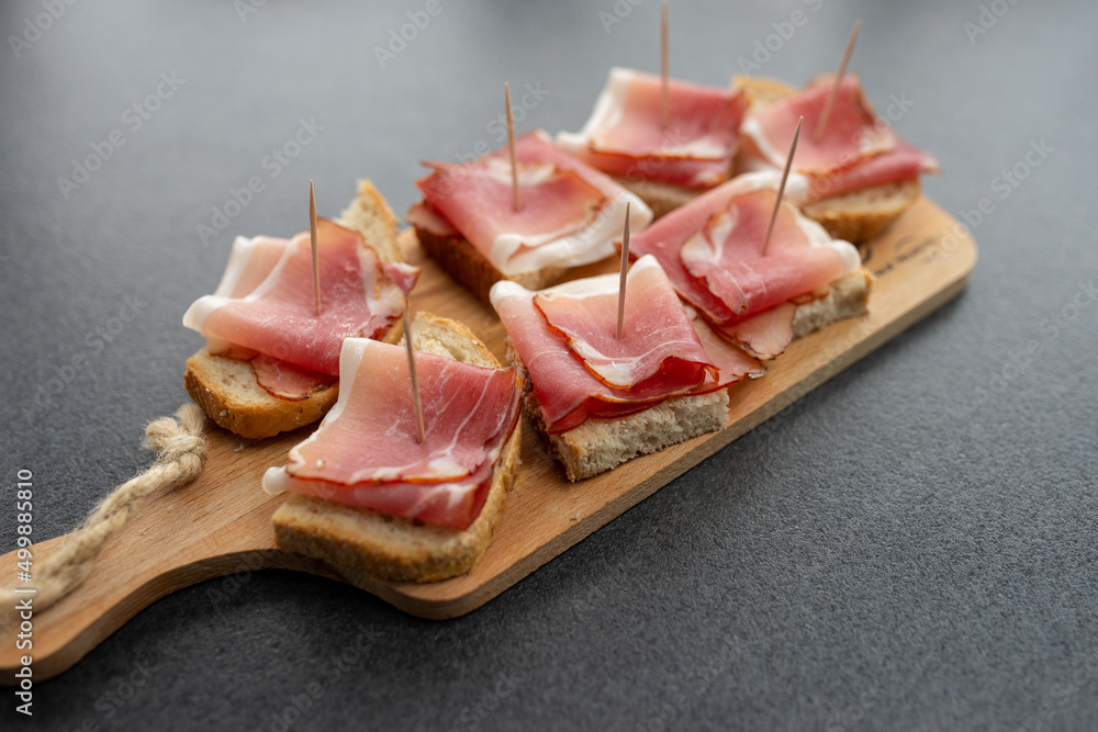 Pieces of bacon thinly sliced on a wooden board. Bread cut for eating.