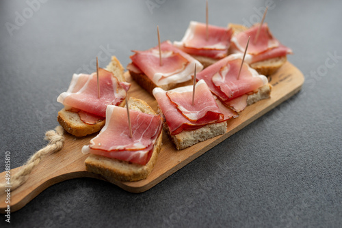 Pieces of bacon thinly sliced on a wooden board. Bread cut for eating.