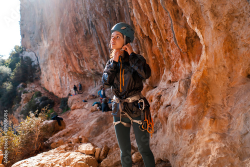 Girl, rock climber puts on a helmet on her head.