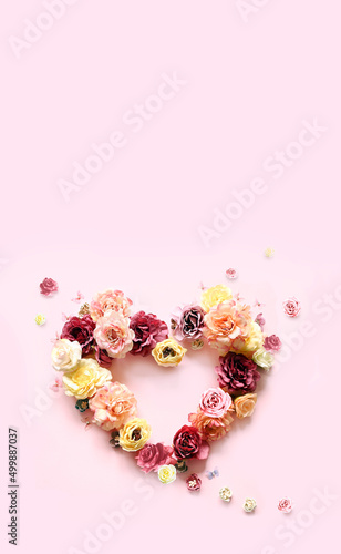 Happy mothers and Valentines day. Bouquet of colorful assorted roses in heart shape on pink background and butterfly.