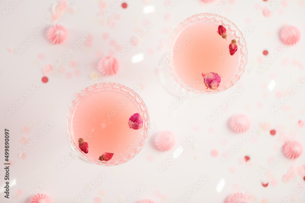 Top view of cocktails in glasses with sweets and confetti on white background.
