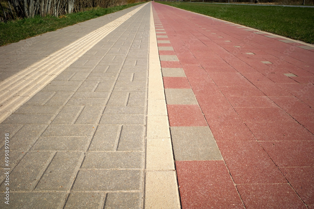 Obraz premium Pedestrian and bike paths converge on the horizon. Perspective. A special relief strip on the pavement for blind people.