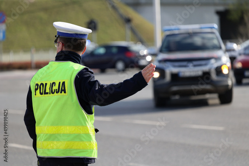 Policjant ruchu drogowego przy swoim radiowozie kontroluje ruch drogowy w mieście. 