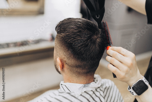 Male barber drying hair of hipster