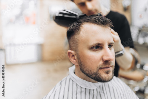 Male barber drying hair of hipster